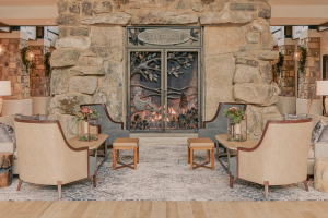 Photo of a sitting area in Dollywood's Heartsong Resort. There is an intricately designed fireplace in the background. The metal screen is engraved with a woman sitting in a tree branch with butterflies and leaves floating around her.